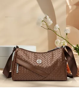 Detail of dark brown woven leather crossbody bag with metal kangaroo logo and wide strap