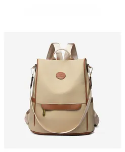 Detail view of beige backpack with brown leather trim and kangaroo emblem on white background