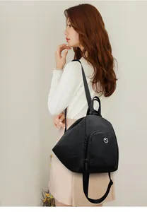 Gros plan d'un sac à dos noir en nylon sur modèle avec bretelles et logo en métal