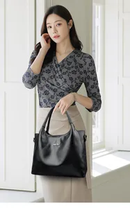 Gros plan du sac cabas noir en cuir grainé avec logo en métal argenté et doubles anses