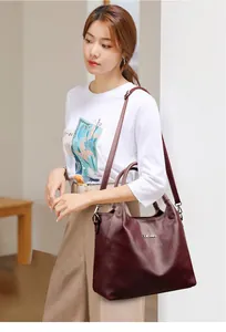 Gros plan du sac cabas en cuir bordeaux vintage avec logo argenté et bandoulière