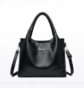 Détail du logo en métal argenté et de la texture en cuir brillant sur ce sac à bandoulière
