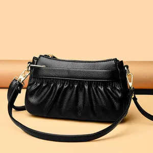 Elegant black lychee leather crossbody bag with pleated design and gold zippers