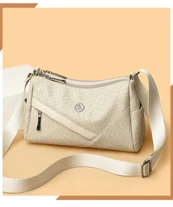 Detail of woven leather texture and circular kangaroo logo on cream crossbody bag