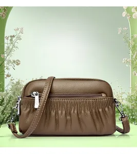 Detailed view of brown leather crossbody bag with pleated finish and silver zippers