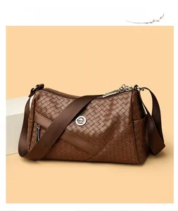 Macro detail of brown woven texture and kangaroo metal logo on a square shoulder bag