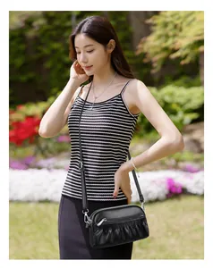 Detail of black leather crossbody bag featuring pleated design and silver zippers