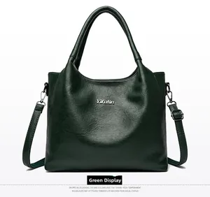 Détail d'un sac en cuir vert foncé avec logo argenté et bandoulière réglable