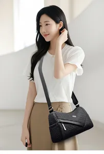 Detail of a black woven leather crossbody bag featuring a round logo and wide nylon strap