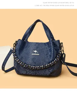 Macro shot of dark blue snakeskin texture leather bag with metal kangaroo logo and chain