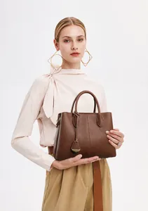 Detailed view of deep brown litchi pattern leather handbag with decorative pendant charm