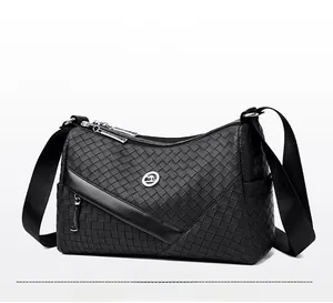 Detail of woven texture and round kangaroo metal logo on a black crossbody bag