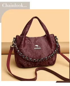 Detailed macro view of burgundy snakeskin texture leather bag with a metal kangaroo logo