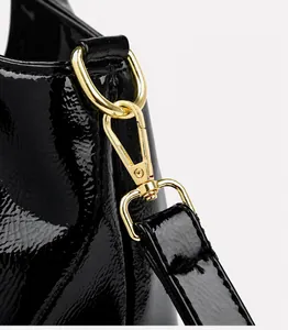 Details einer glänzenden schwarzen Lackledertasche mit hochwertigen goldenen Metallteilen