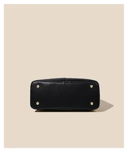 Close-up of black lychee grain leather handbag base with four gold protective metal feet