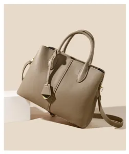Detail view of khaki pebbled leather handbag with gold-tone hardware and leather pendant
