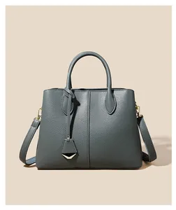 Close-up of grey-blue leather handbag featuring litchi texture and gold hardware details