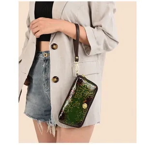 Detail of green patent leather clutch featuring 3D peony relief and elegant gold hardware