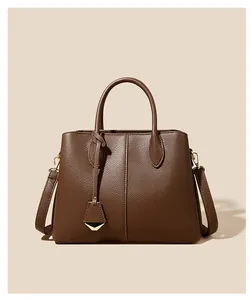 Detailed view of dark brown pebbled leather texture on a trapezoid handbag with a gold pendant