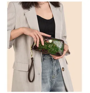 Detail of vintage embossed rose pattern on green patent leather clutch with gold zipper