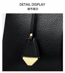 Close-up of black lychee-grain leather texture with a gold triangle pendant detail