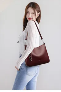 Detail of burgundy pebbled leather bucket bag with silver hardware and adjustable strap