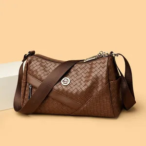 Deep brown woven leather crossbody bag with kangaroo metal logo on a minimalist background