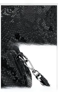 Detail of black snake embossed texture fabric and silver metal clasp on the handbag strap