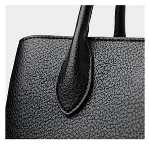 Close-up of litchi grain cowhide leather and fine stitching on the black handbag
