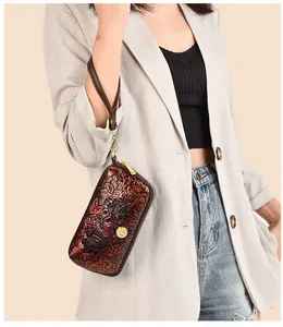 Detail of embossed peony pattern on genuine leather vintage clutch bag with gold hardware