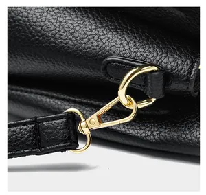 Detail of gold lobster clasp and D-ring on black litchi grain leather shoulder bag