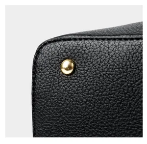 Close-up of black lychee leather handbag with protective gold metal bottom studs