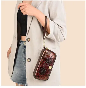 Detail of red embossed floral clutch bag with gold zipper and detachable wrist strap
