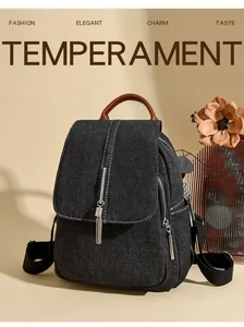 Detail of black denim backpack with silver tassel charm and brown leather handle