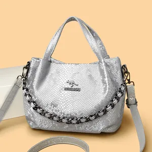 Silver snake pattern tote bag with metal chain and kangaroo logo on warm background
