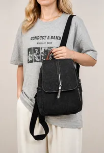 Detail of a black denim backpack featuring silver tassels and brown leather top handle