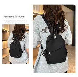 Detail of black nylon mini backpack featuring orange side label and diagonal zipper pocket
