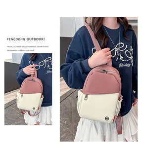 Detail of pink and beige crossbody bag showing side pocket and metal logo placement