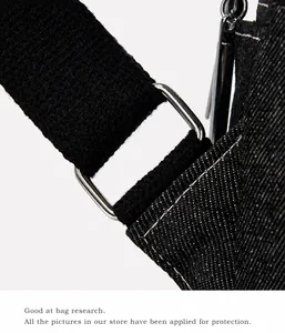 Detailed macro view of black denim bag fabric with white stitching and silver metal rings