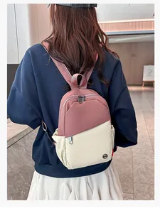 Detail of pink and beige contrast backpack with multiple zipper pockets on model