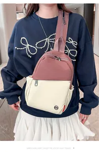 Macro view of two-tone nylon sling bag showing circular metal LST logo and zip pockets