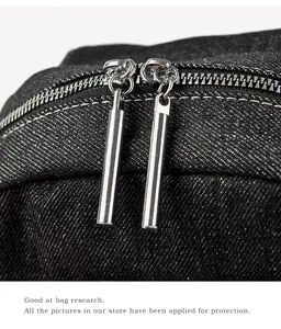 Detailed macro view of silver dual cylinder zippers on black washed denim fabric
