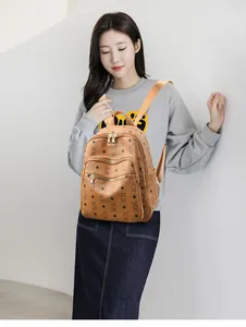 Close-up of brown faux leather backpack with bear monogram print and gold zippers