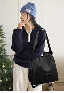 Détail d'un sac à dos plissé noir avec logo kangourou dans un décor de vacances