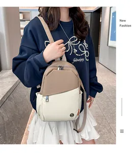 Detailed view of the khaki and cream nylon backpack featuring a round metal logo plate