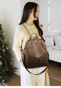 Gros plan sur le sac à dos marron foncé imperméable avec plaque de marque et zip en métal