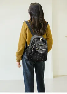 Detail of black monogram backpack on model showing size and gold hardware accents
