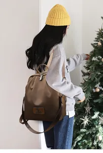 Gros plan du sac à dos en nylon marron avec écusson en cuir logo kangourou et double zip
