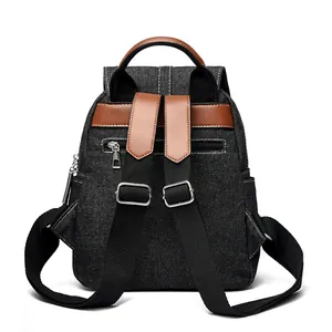 Washed denim backpack with chain fringe and adjustable leather straps in back view