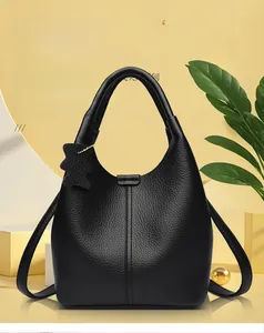 Detail of black pebbled leather bucket bag with bear charm and vertical stitching accents